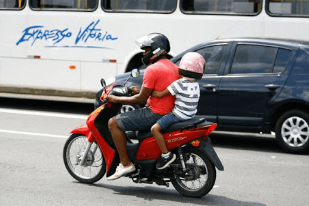 Imagem de criança na moto abraçando o motociclista