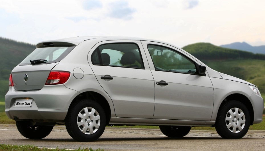 Foto mostrando a traseira de um Volkswagen Gol 2009 G5 estacionado em uma rua de asfalto cercada de grama.