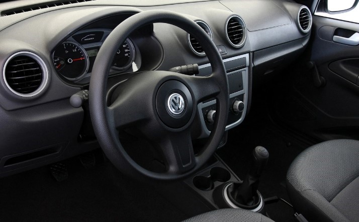 Foto mostrando o interior do carro. É possível ver o painel, o volante, os controles e as saídas de ar, o câmbio e o espaço dos bancos dianteiros.