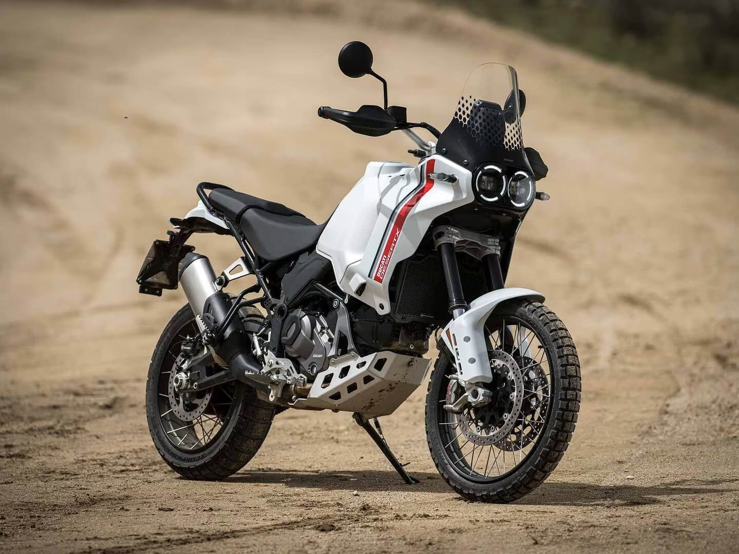 Foto da Ducati DesertX estacionada em uma estrada de terra