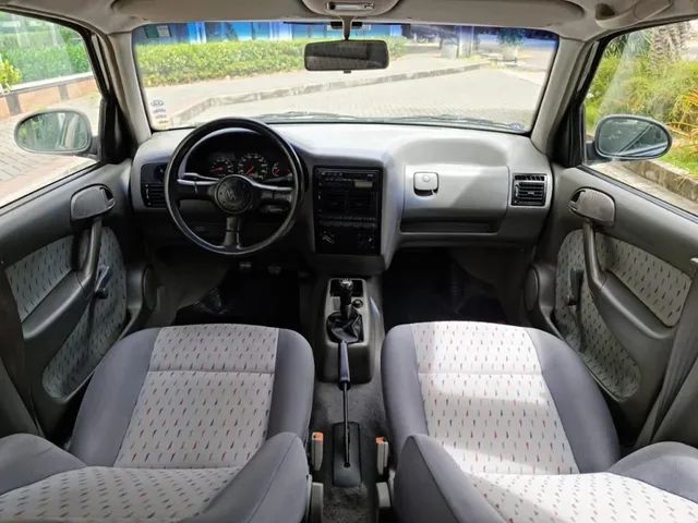 Foto interna do Volkswagen Gol 16v, exibindo o volante, o painel de instrumentos, parte das portas e bancos.