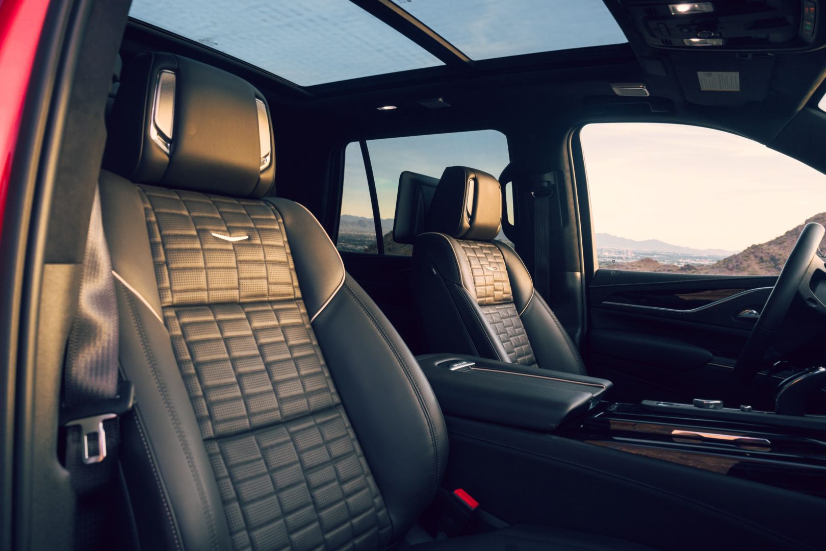 Foto interna do Cadillac Escalade V 2023, exibindo os bancos dianteiros e o teto solar panorâmico.