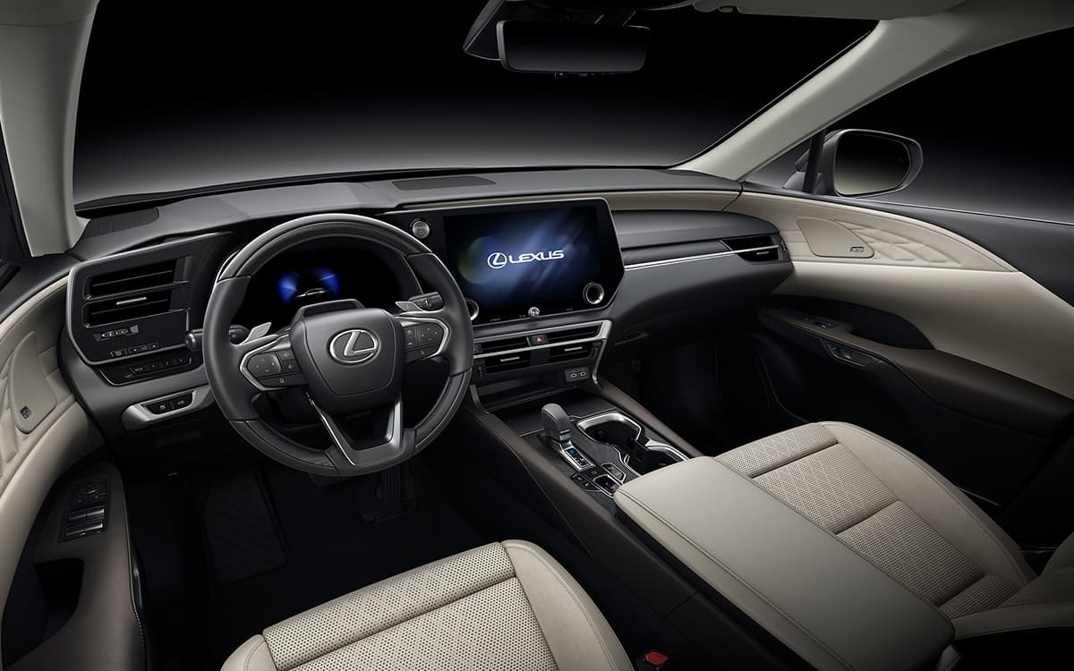 Foto interna do Lexus RX 450h PHEV 2025, exibindo o painel de instrumentos digital. volante multifuncional, central multimídia e parte dos bancos.